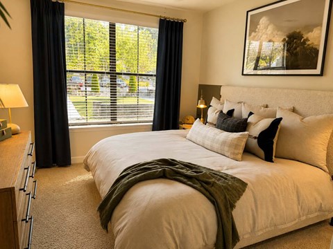 A bedroom with a large bed and a window with blinds.