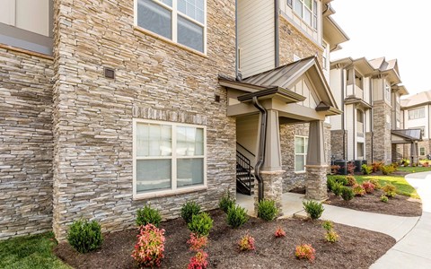 a view of the exterior of an apartment building with a sidewalk in front of it