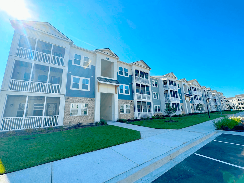 A row of modern apartment buildings with balconies and green lawns.