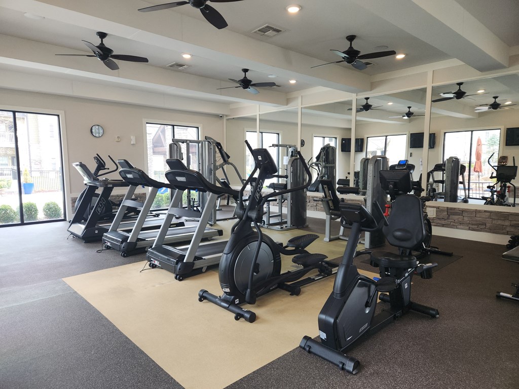 a gym with various exercise machines and ceiling fans