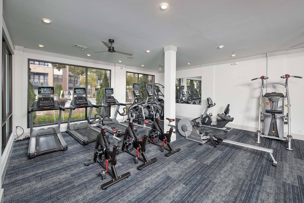 A gym with a variety of exercise equipment including treadmills, stationary bikes, and weight machines.