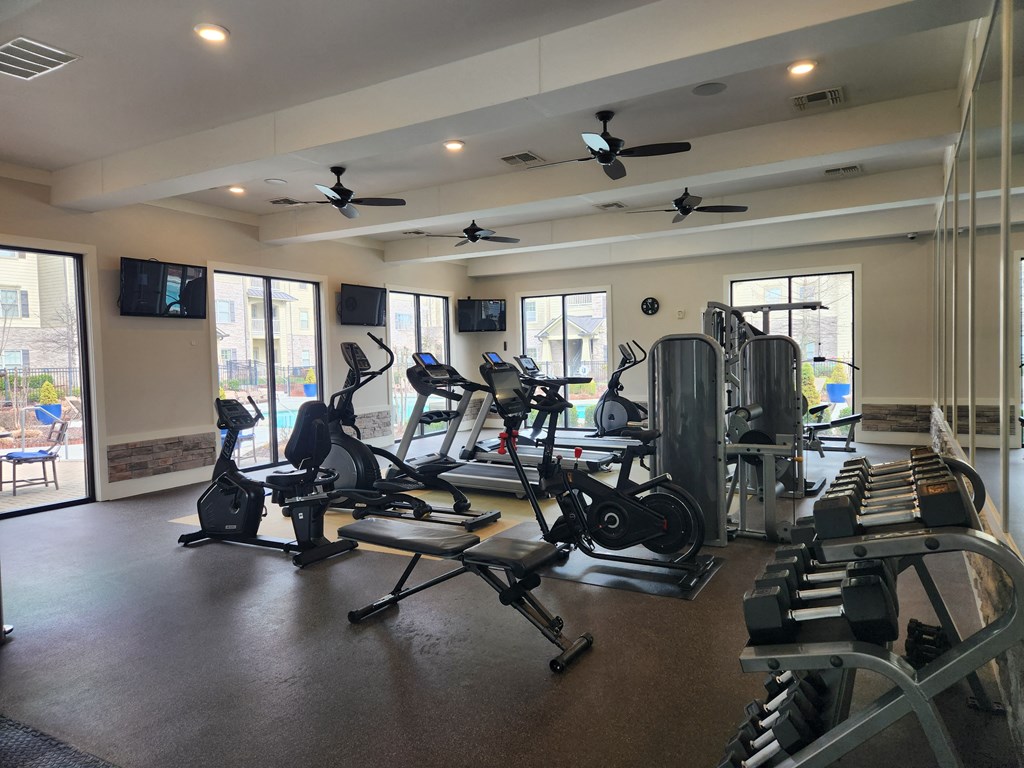a gym with cardio equipment and ceiling fans