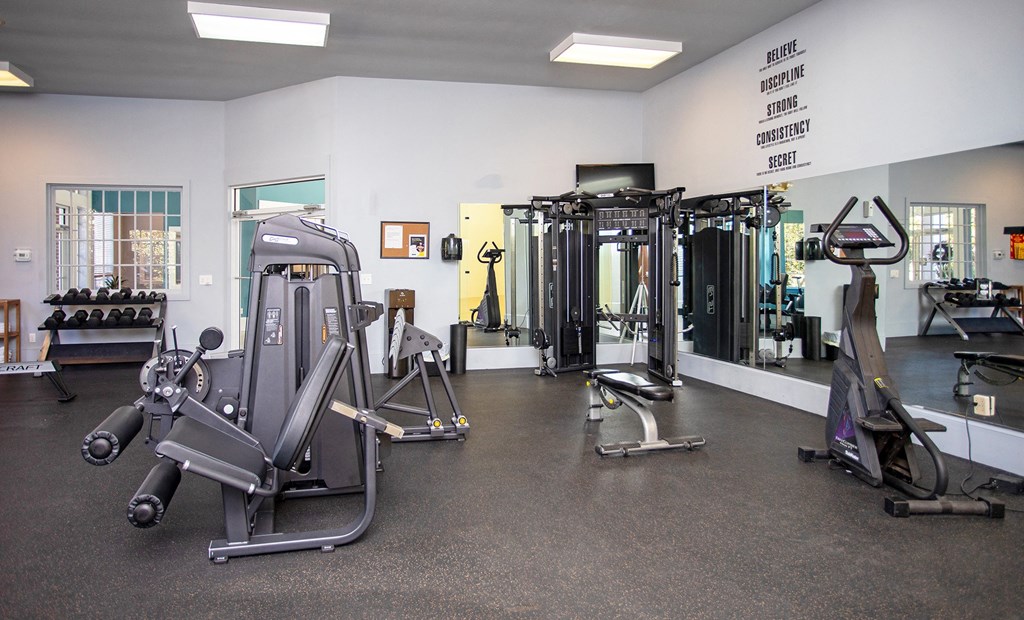 a large fitness room with cardio equipment and weights