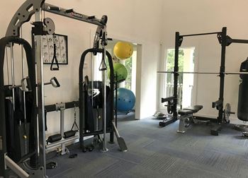 A gym with a variety of equipment including a weight bench, a leg press machine, and a squat rack.