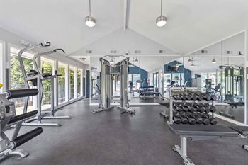 A spacious gym with a variety of equipment and a large mirror on the wall.