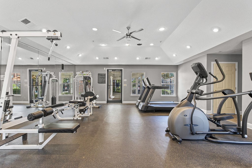 A spacious gym with a variety of equipment including treadmills, weights, and a stationary bike.