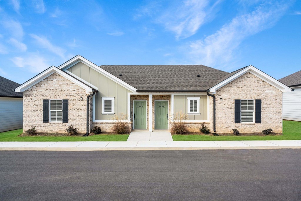 a house with a green front door and brick and white walls