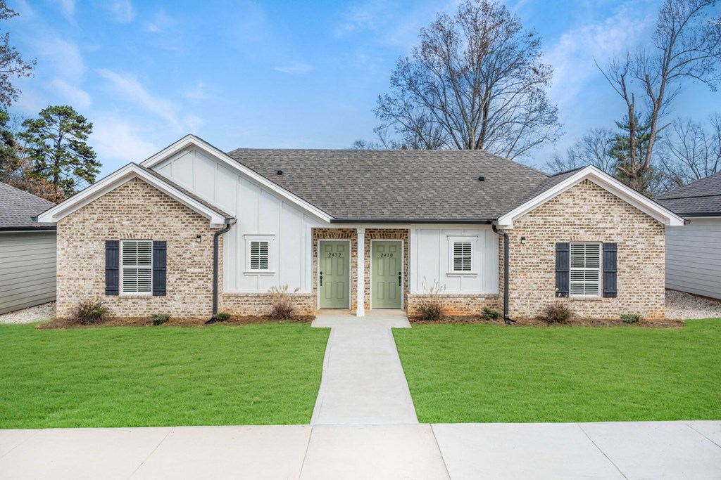 a white house with a green front door and a lawn
