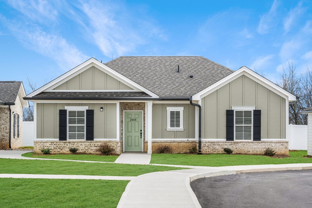 a house with a green door on the side of a driveway