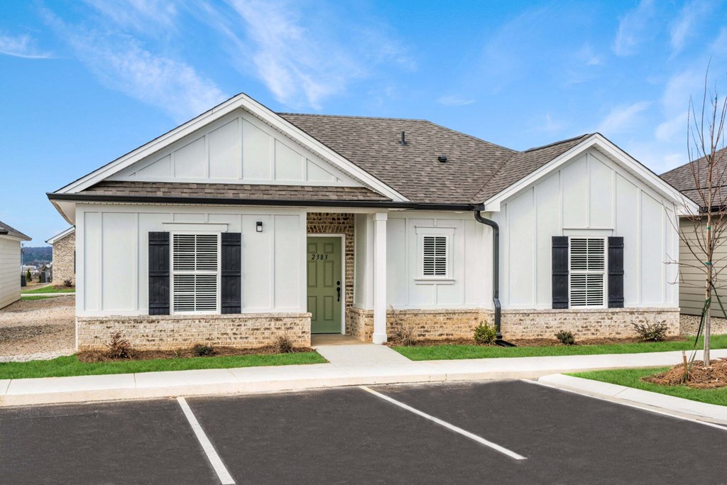 a white house with a green door and a driveway