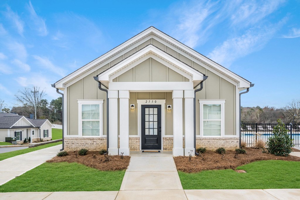 the exterior of a home with a black door and a sidewalk in front of it