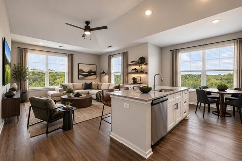 A modern kitchen and living room with a ceiling fan and large windows.
