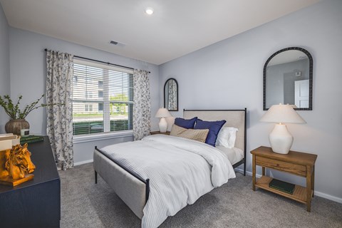 A bedroom with a large bed and a nightstand with a lamp.