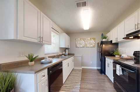 A kitchen with white cabinets and a black refrigerator.
