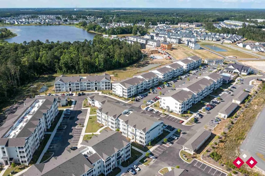 A bird's eye view of a residential complex with multiple buildings and a parking lot.