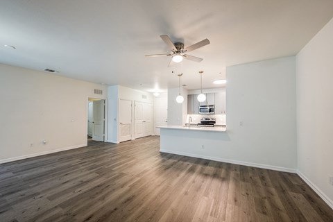 A spacious room with a ceiling fan and wooden flooring.