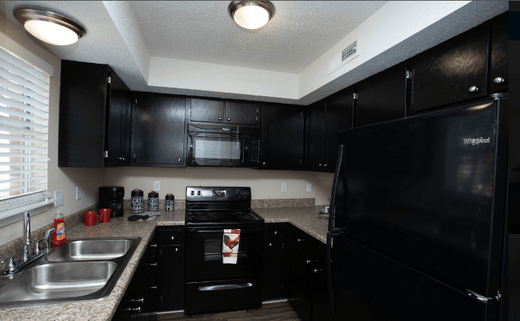 a kitchen with black cabinets and granite countertops