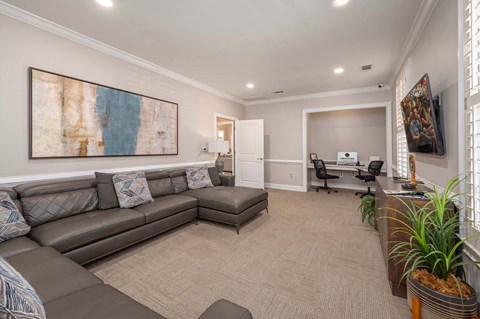A living room with a grey couch and a painting on the wall.