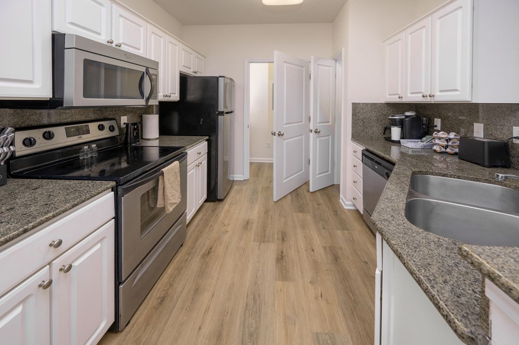 A kitchen with black appliances and white cabinets.