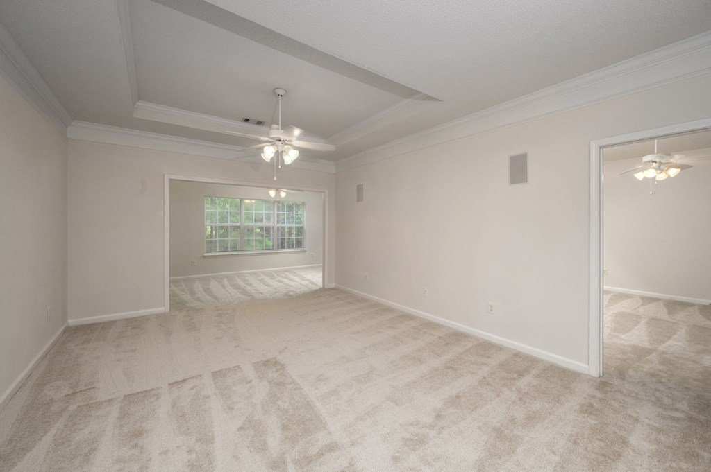 A room with a carpeted floor and a ceiling fan.