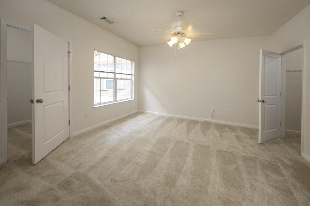 A room with a carpeted floor and a window letting in natural light.
