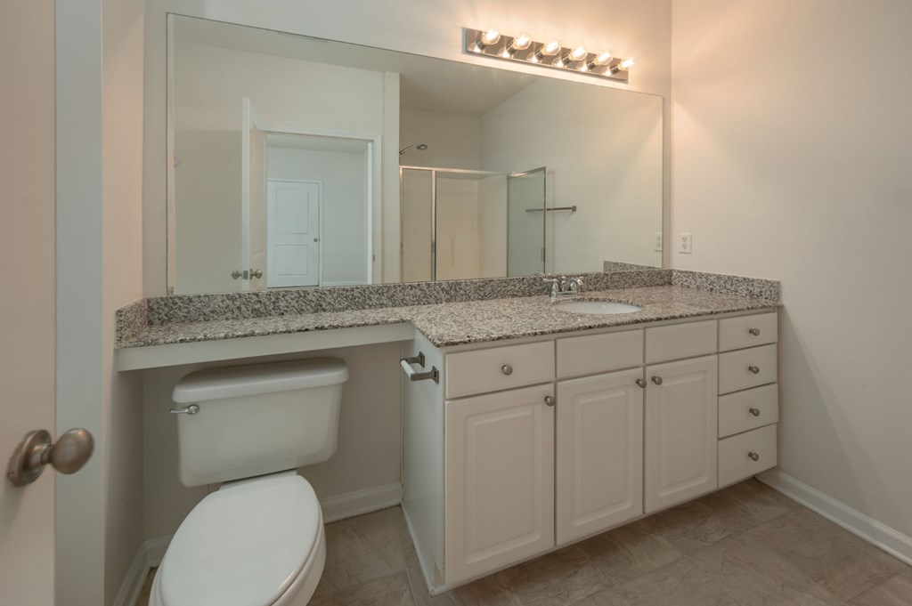 A bathroom with a toilet, sink, and mirror.