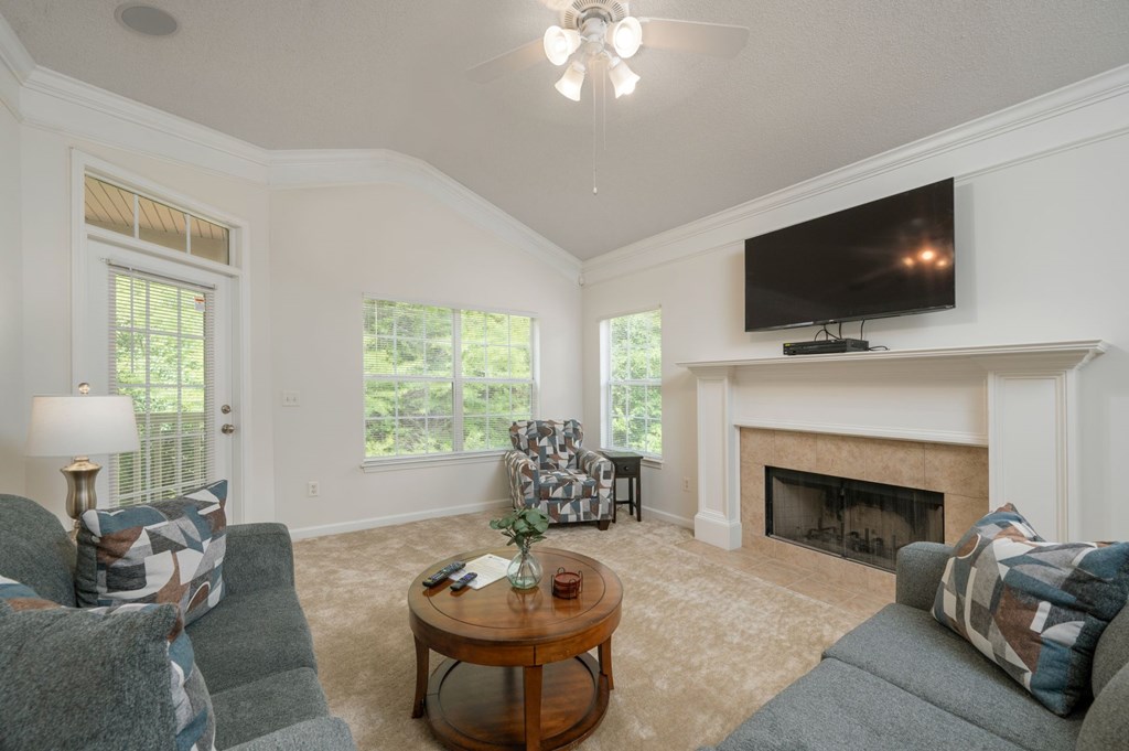 A living room with a fireplace and a television mounted above it.