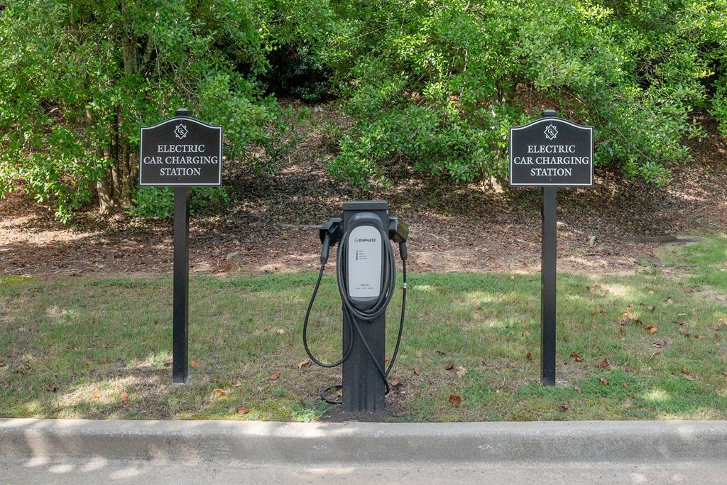 Two signs that say Electric Car Charging Station stand behind a charger.