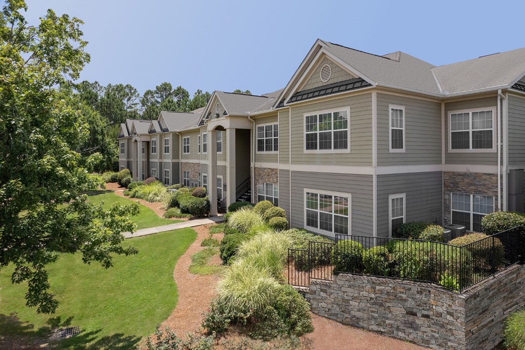 A large grey house with a stone wall in front.