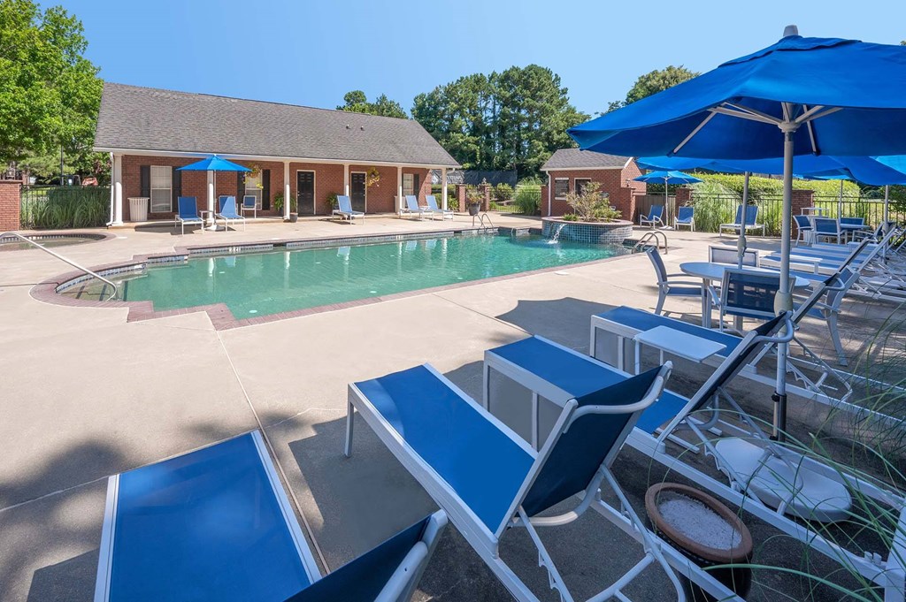 A pool area with sun loungers and a building in the background.