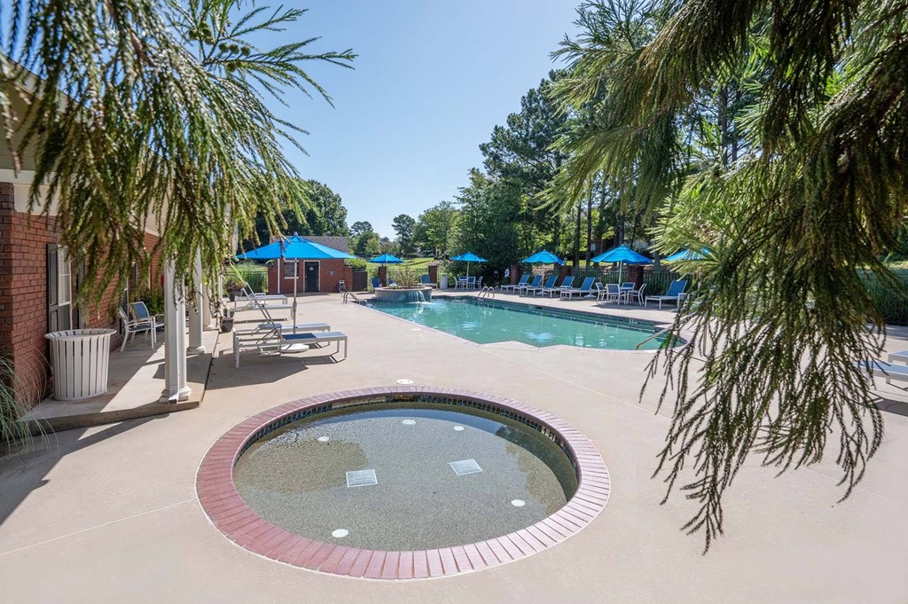 A pool surrounded by trees and umbrellas.