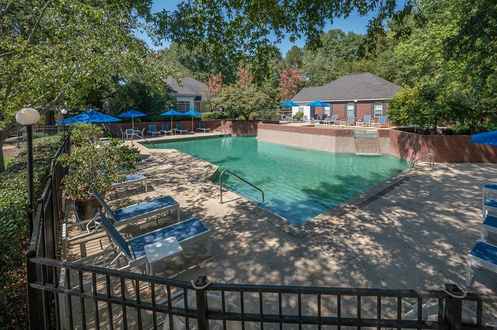 A pool surrounded by trees and a fence.