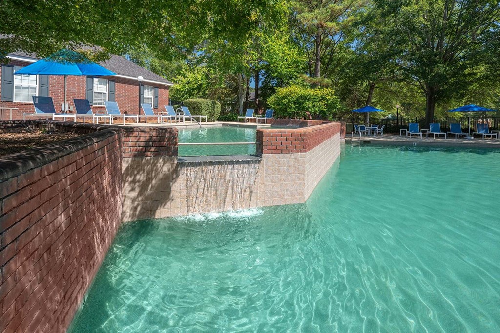 A swimming pool surrounded by a brick wall and trees.