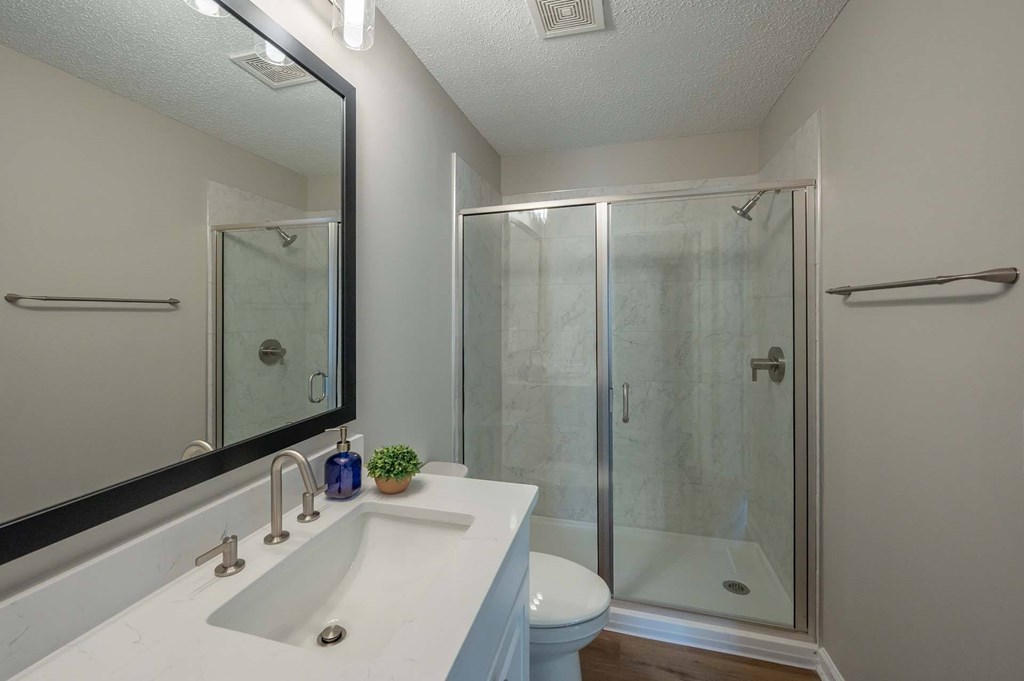 A white sink with a mirror above it and a toilet behind it.