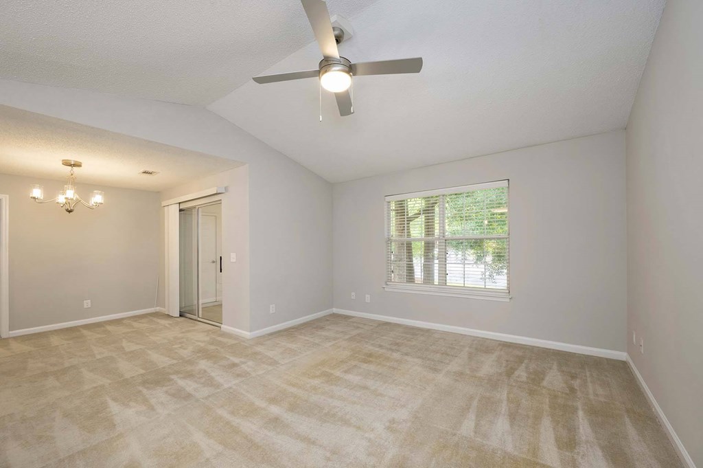 A room with a ceiling fan and a window with blinds.