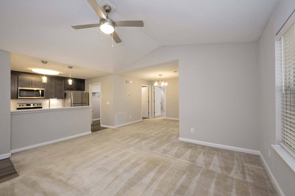 A spacious living room with a ceiling fan and lighting fixtures.