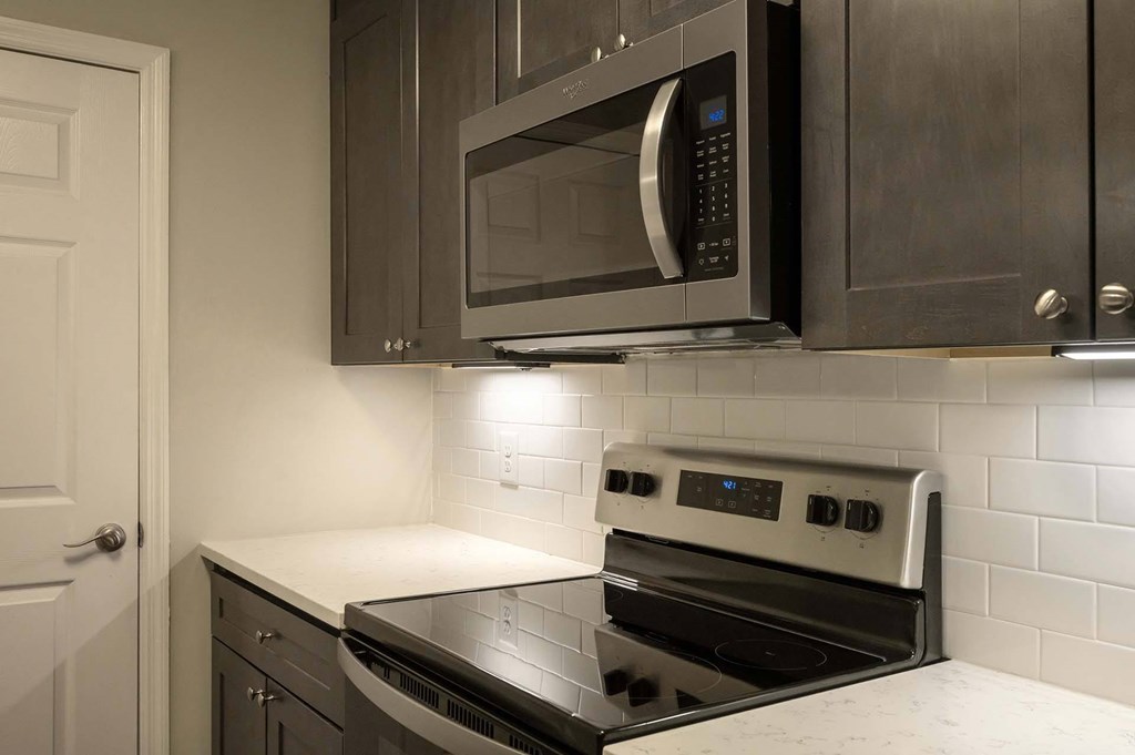 A modern kitchen with a black stove top oven and microwave above it.