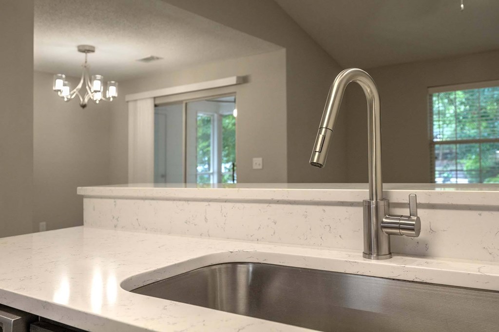 A modern kitchen with a stainless steel sink and a silver faucet.
