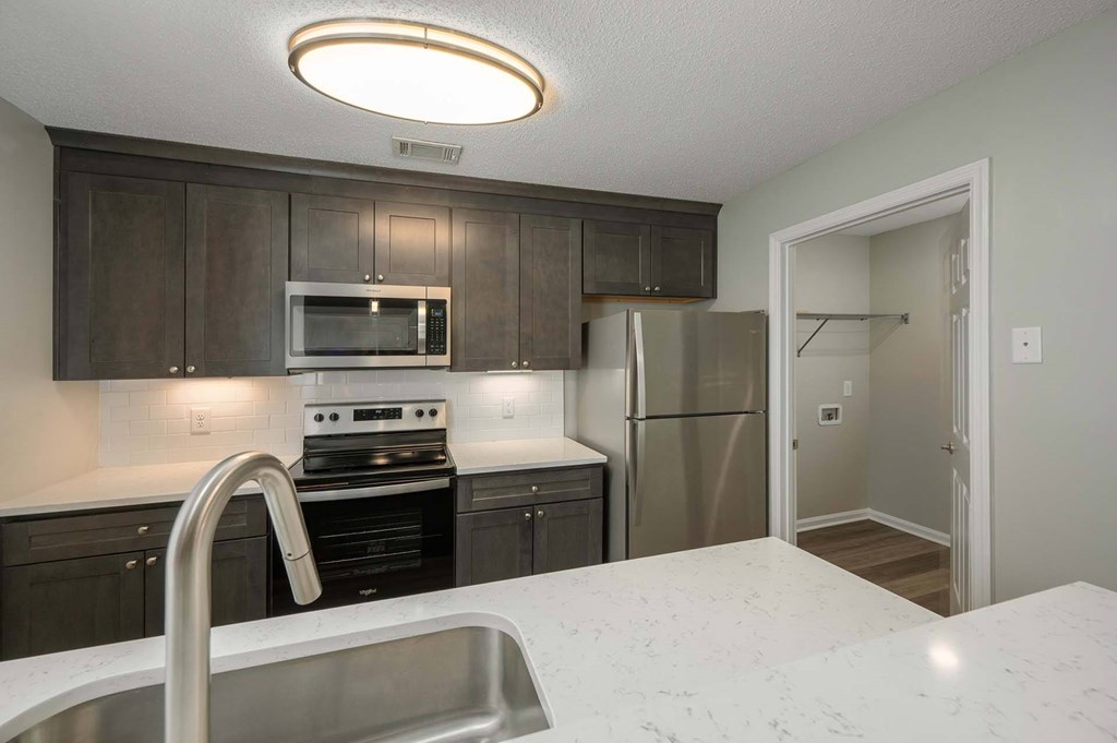 A kitchen with a stove, refrigerator, and microwave.