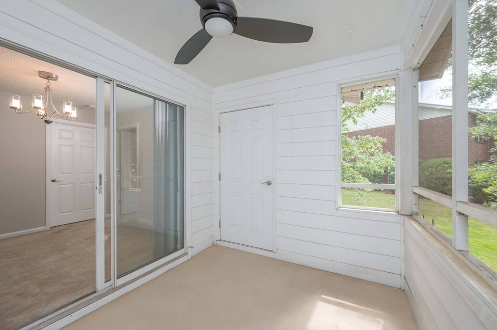 A sunny room with a ceiling fan and sliding glass doors.