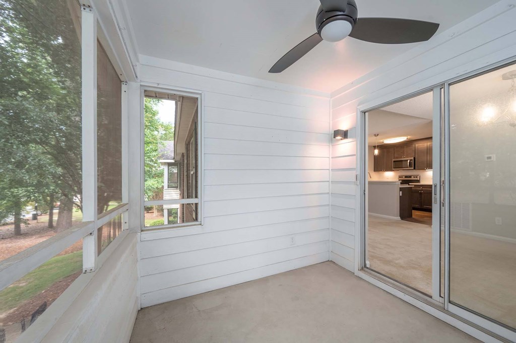 A room with a ceiling fan and sliding glass doors.