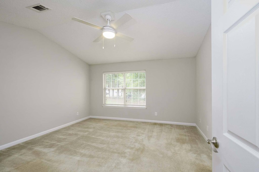 A room with a ceiling fan and a window with blinds.