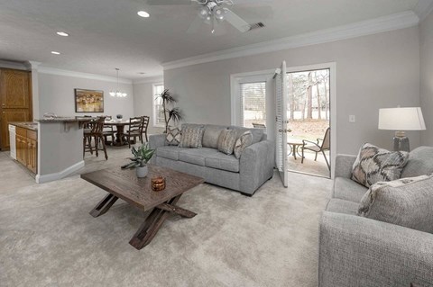 A living room with a grey couch, a wooden coffee table, and a dining table with chairs.