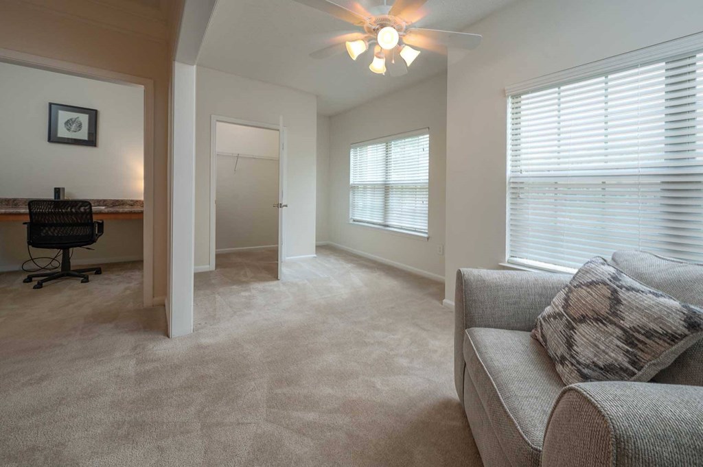 A living room with a couch, a chair, and a window with blinds.