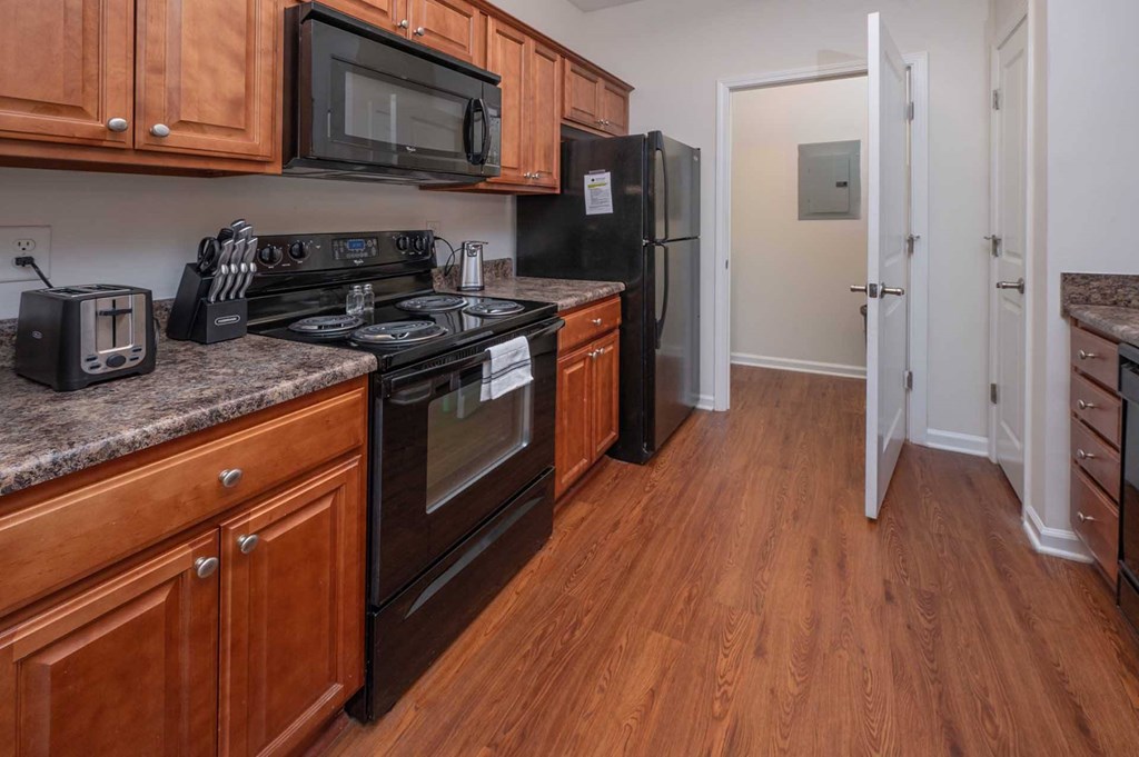A kitchen with black appliances and wooden cabinets.