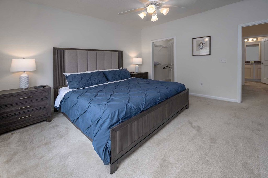 A bedroom with a large bed and a ceiling fan.