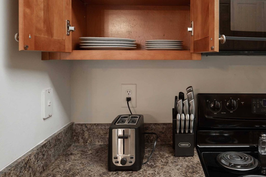 A kitchen with a toaster and knives on the counter.