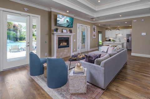A living room with a grey couch, a fireplace, and a television mounted on the wall.