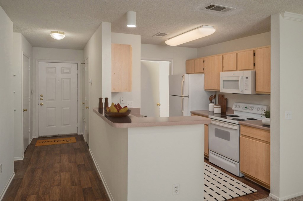 A kitchen with white appliances and wooden cabinets.