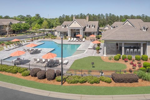 A large swimming pool surrounded by orange umbrellas and lounge chairs.